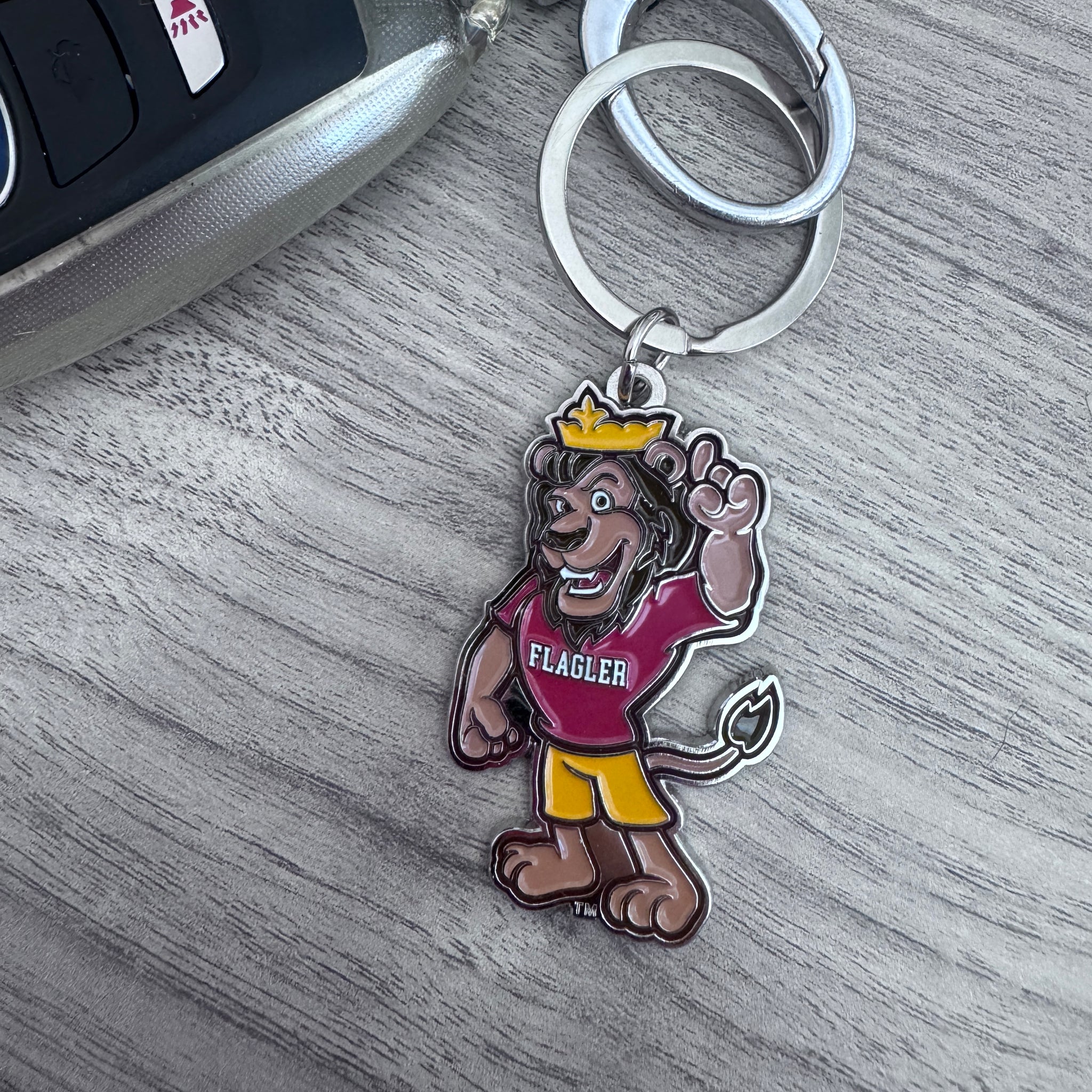 Keychain with cartoon Lewis character wearing a crown and 'Flagler' shirt on a wooden surface.