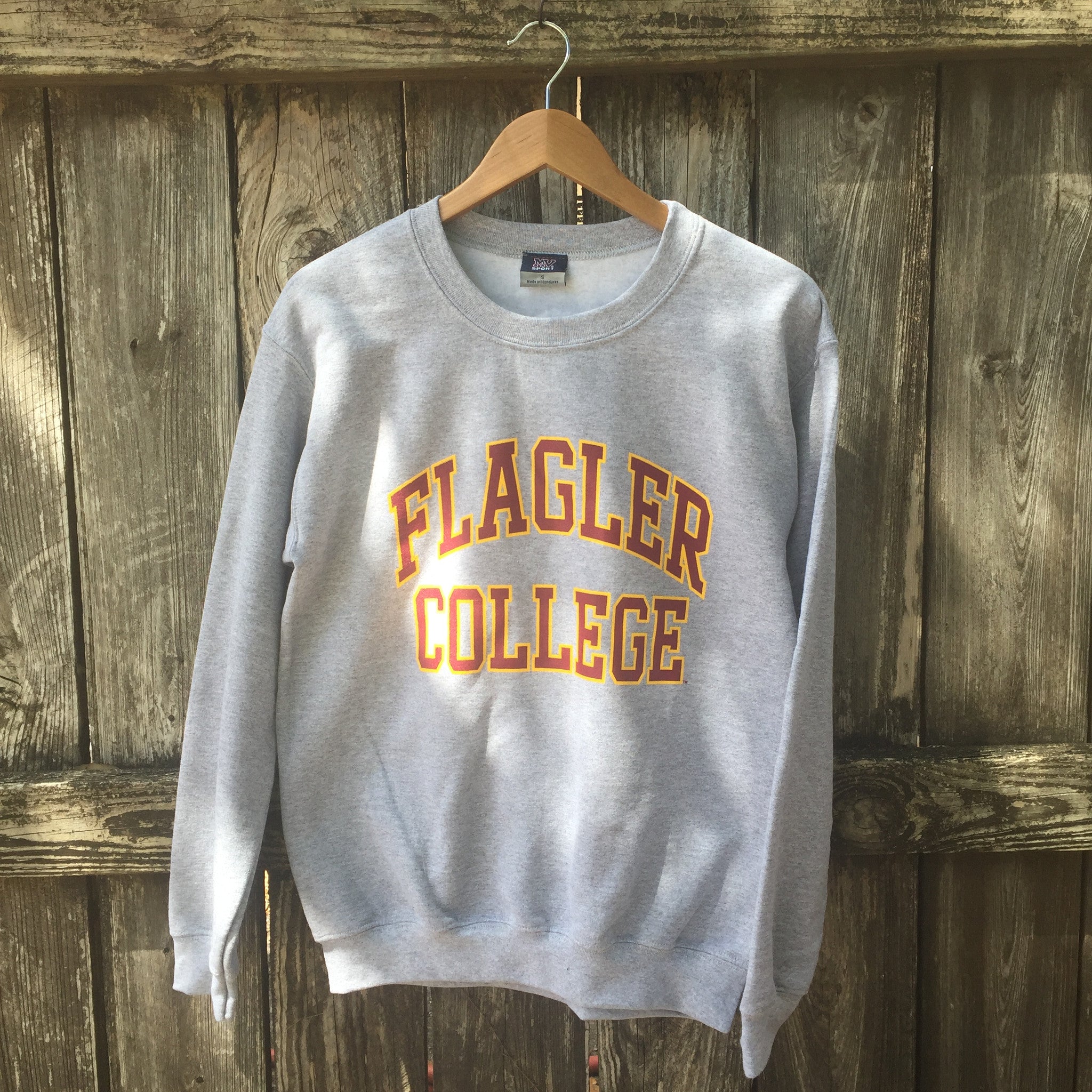 Grey crewneck sweatshirt with crimson with yellow boarder imprint saying Flagler over College