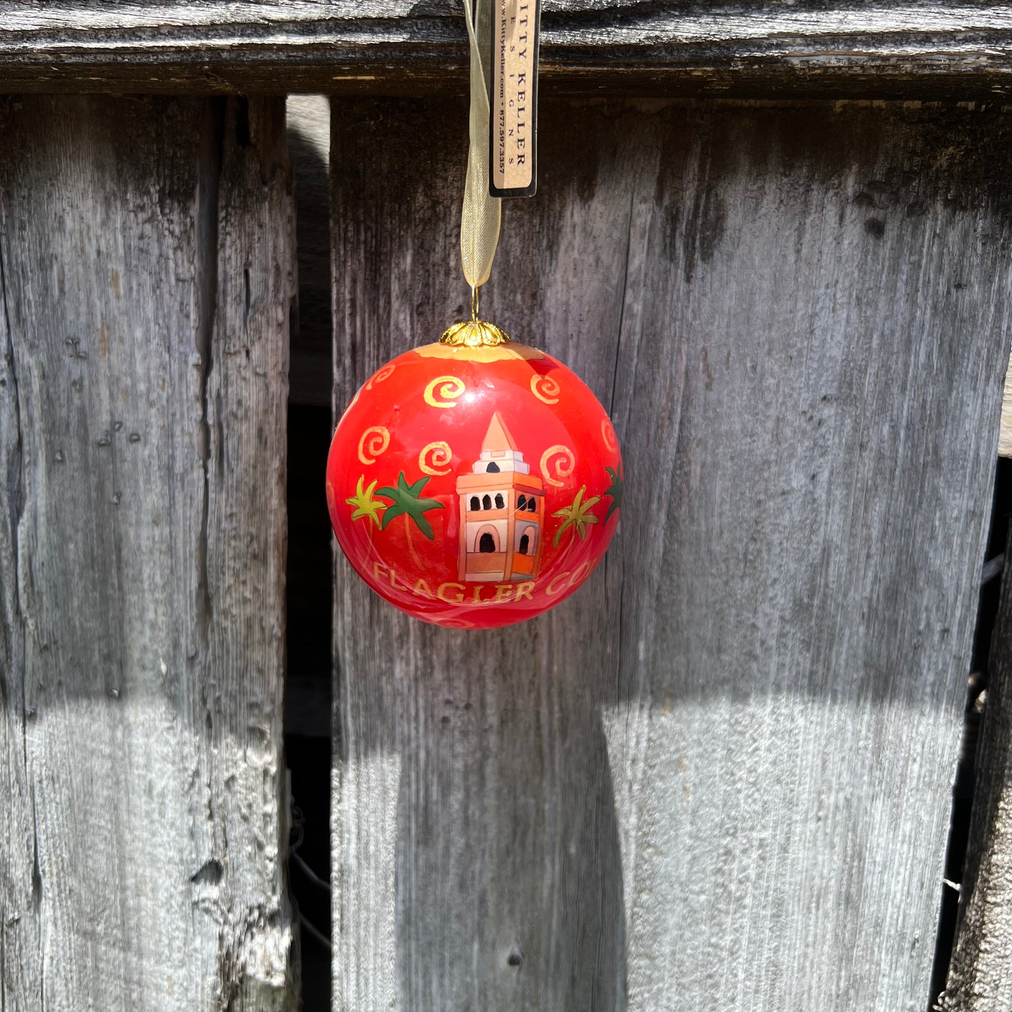 Red hand painted ornament with Ponce de Leon structure over gold letters saying Flagler College