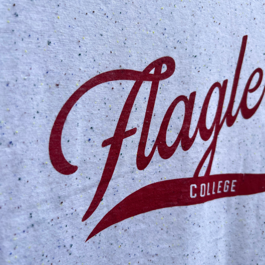 White t-shirt with color flecks with crimson cursive imprint saying Flagler with red swoop with white imprint saying college inside the swoop