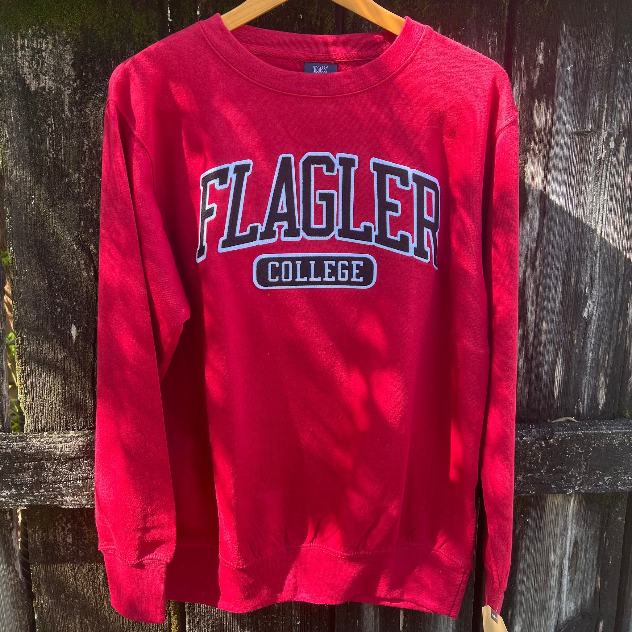 Crimson crewneck with black applique with white imprint saying Flagler over College