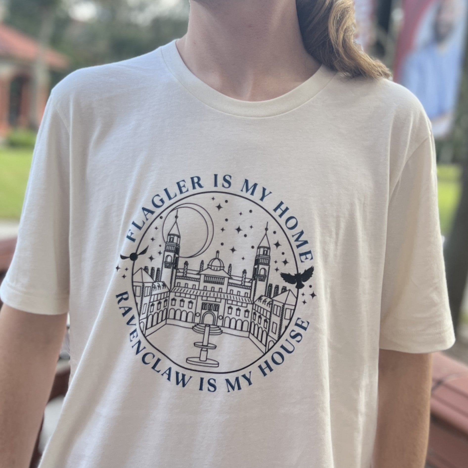 Natural t-shirt with blue imprint saying Flagler Is My Home over black outline of Ponce De Leon over blue imprint saying Ravenclaw Is My House