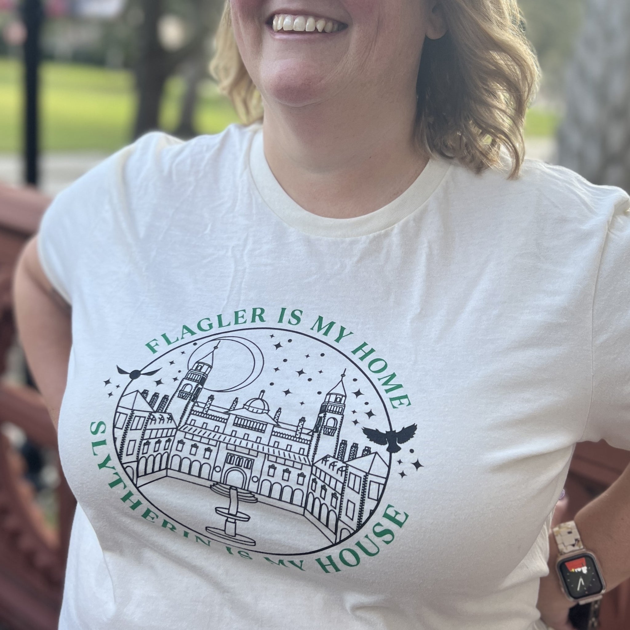 Natural t-shirt with green imprint saying Flagler Is My Home over black outline of Ponce De Leon over green imprint saying Slytherin Is My House