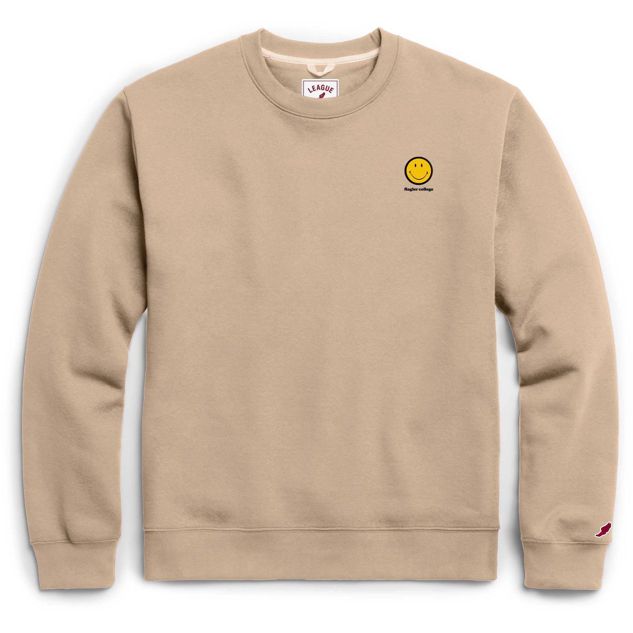 Beige crewneck with yellow smiley face patch over black imprint saying Flagler College