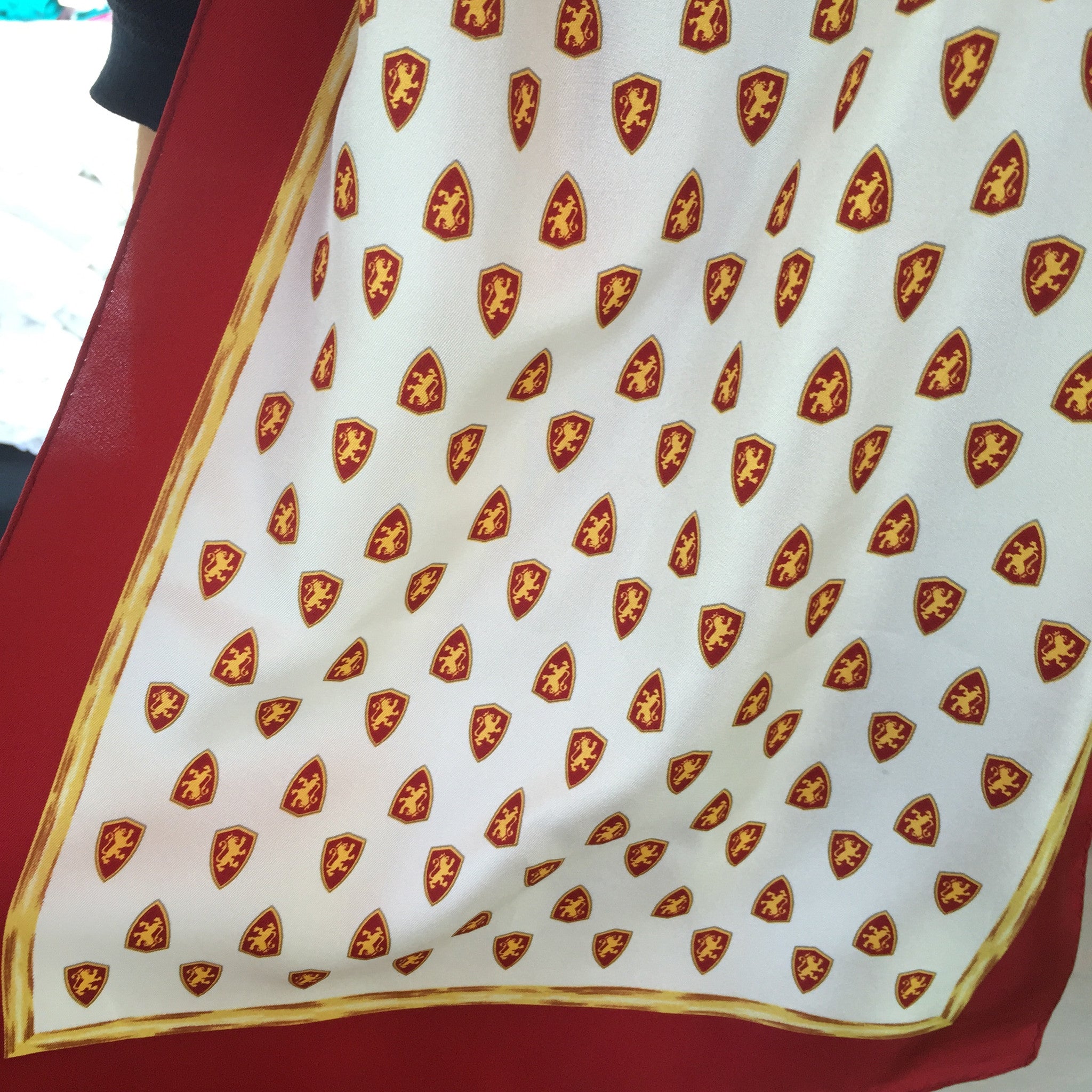 Silk scarf with red and gold border with Flagler College shield logo throughout white center