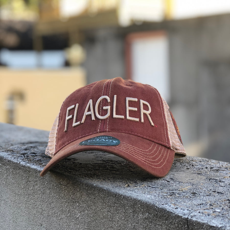 red hat with dirty effect with beige mesh back. Beige embroider saying Flagler and flagler college shield logo on the side of mesh