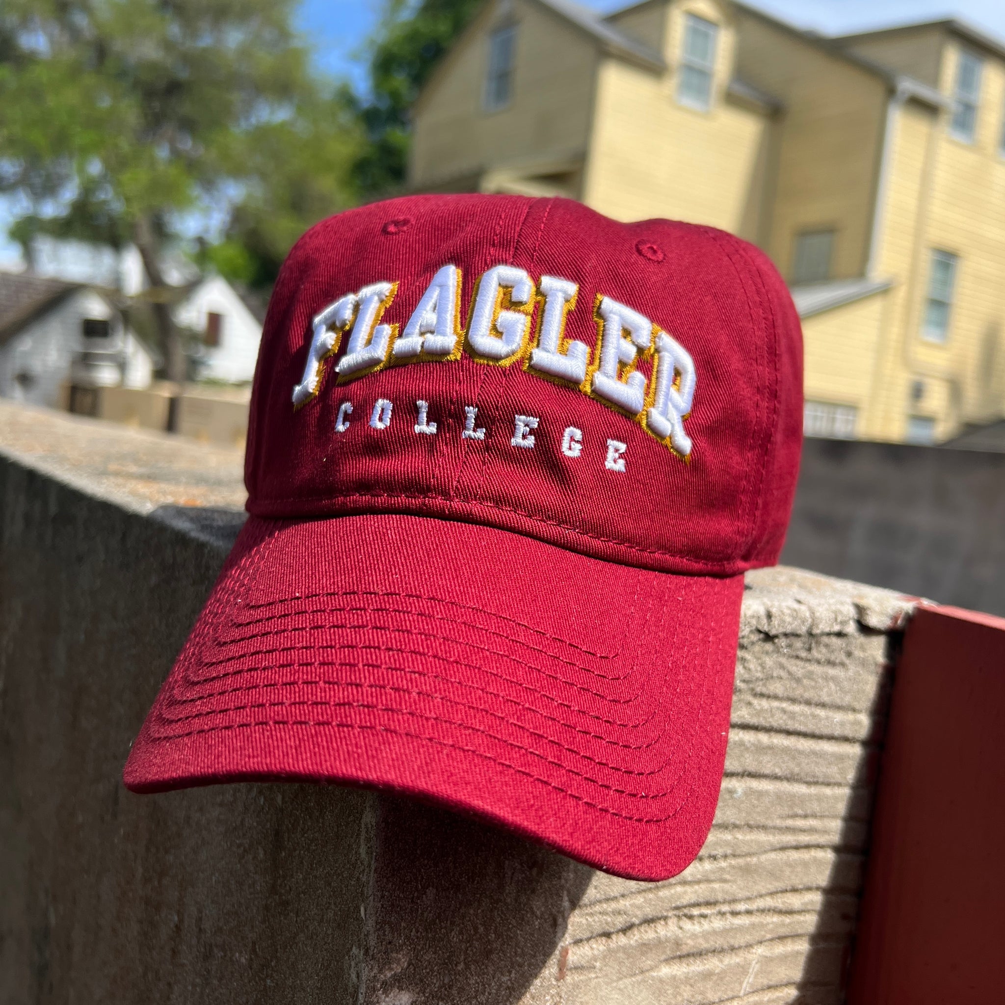 Red hat with white letters saying flagler over white embroider saying College