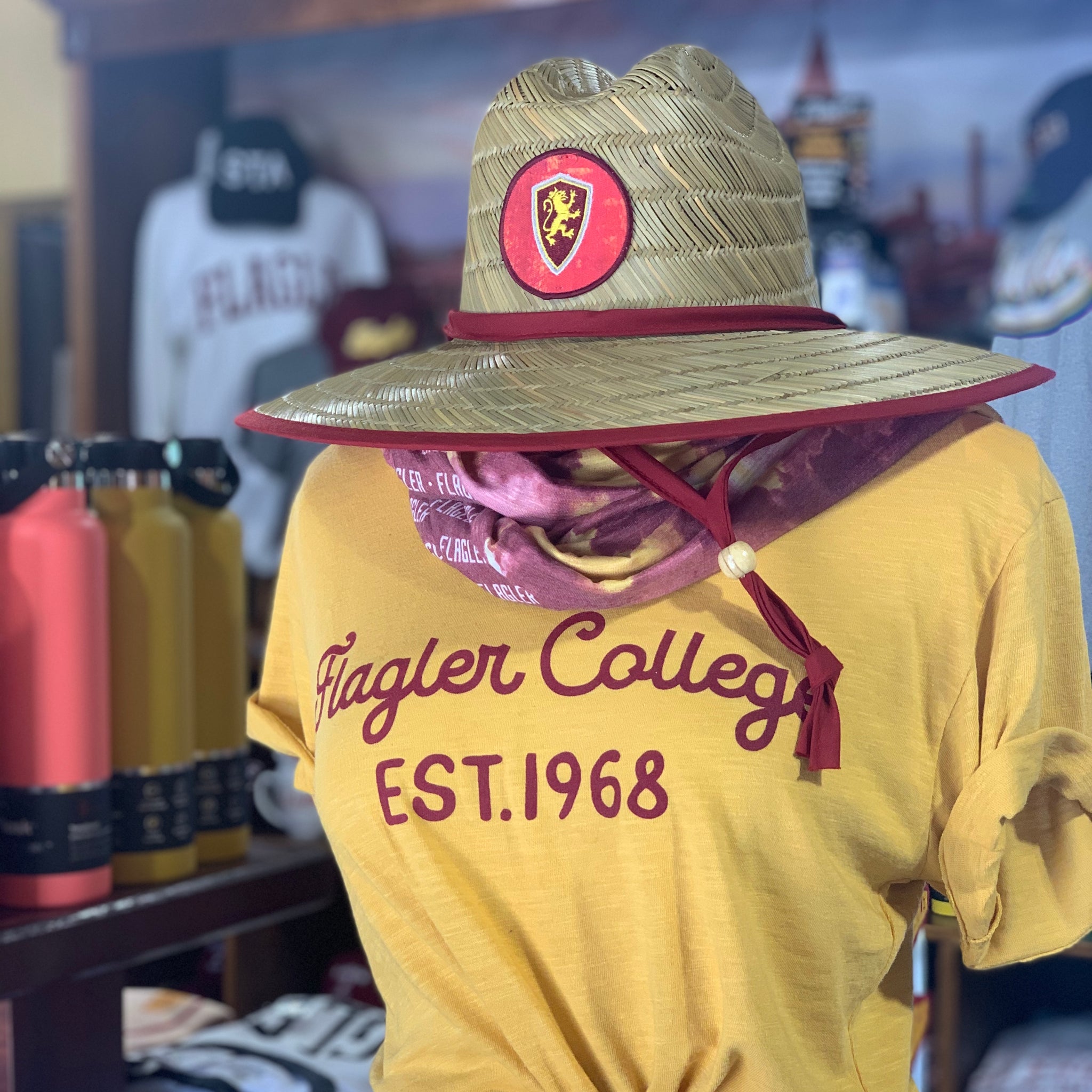 Straw hat with patch in center with Flagler College Shield Logo with crimson drawstring