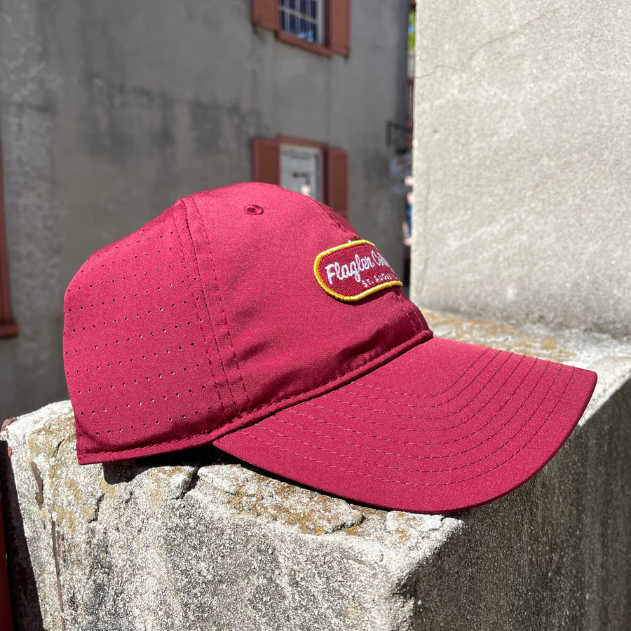 Crimson hat with crimson patch with yellow boarder and white cursive embroider saying Flagler College over print St. Augustine