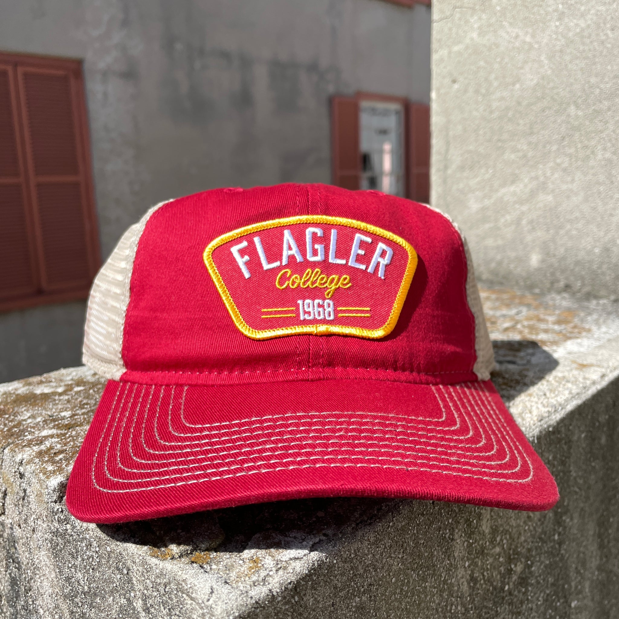 Red hat with beige mesh back. red with yellow outline patch White embroider saying flagler over yellow cursive college over 1968