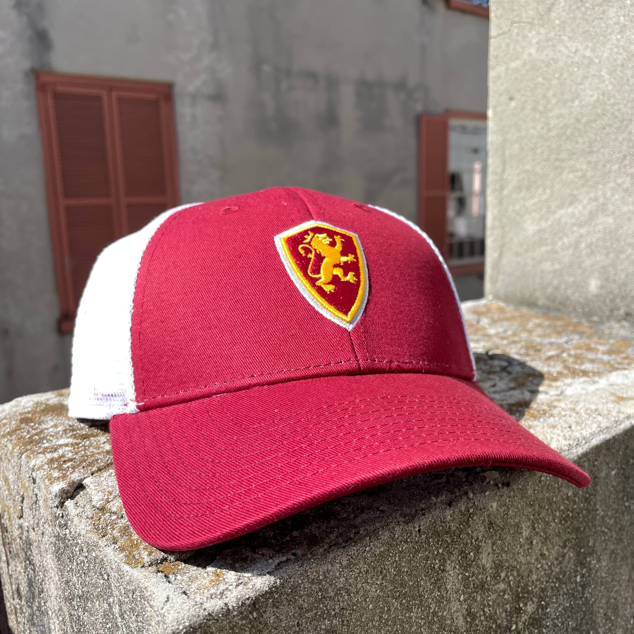 Crimson hat with white mesh and Flagler College Shield logo in center