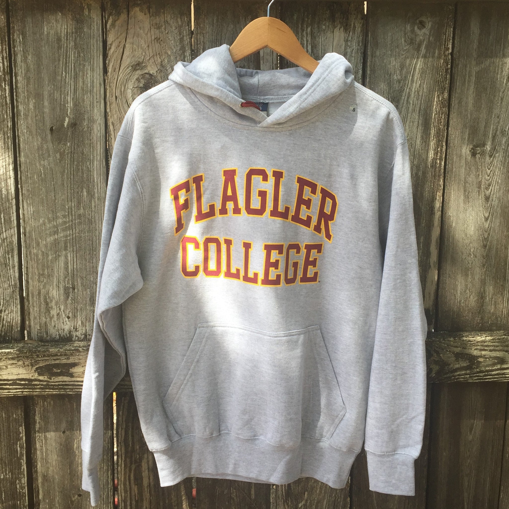 Grey hooded sweatshirt with crimson with yellow boarder imprint saying Flagler over College