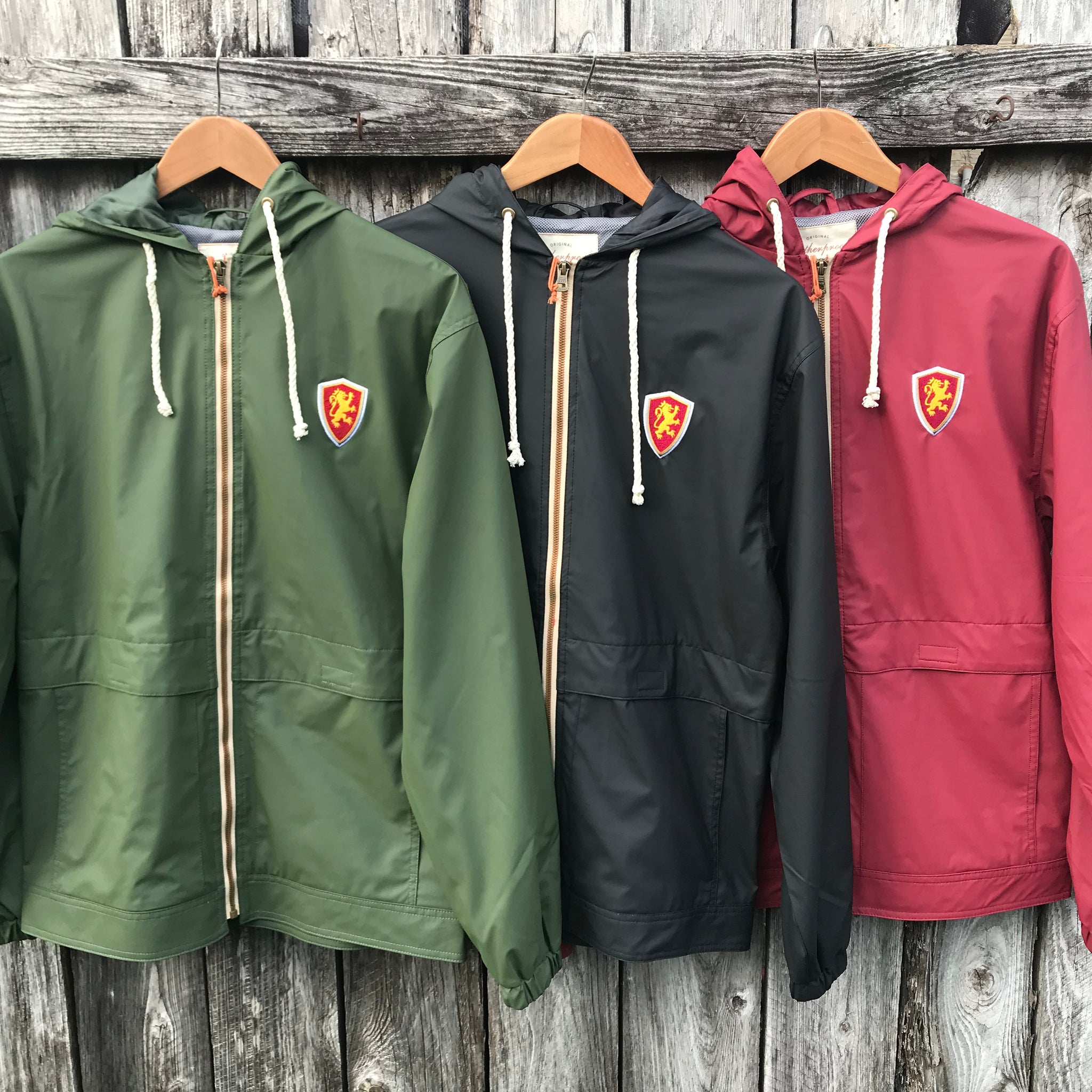 Green, black and red hooded rain jackets. each has red and gold lion shield patch on left chest