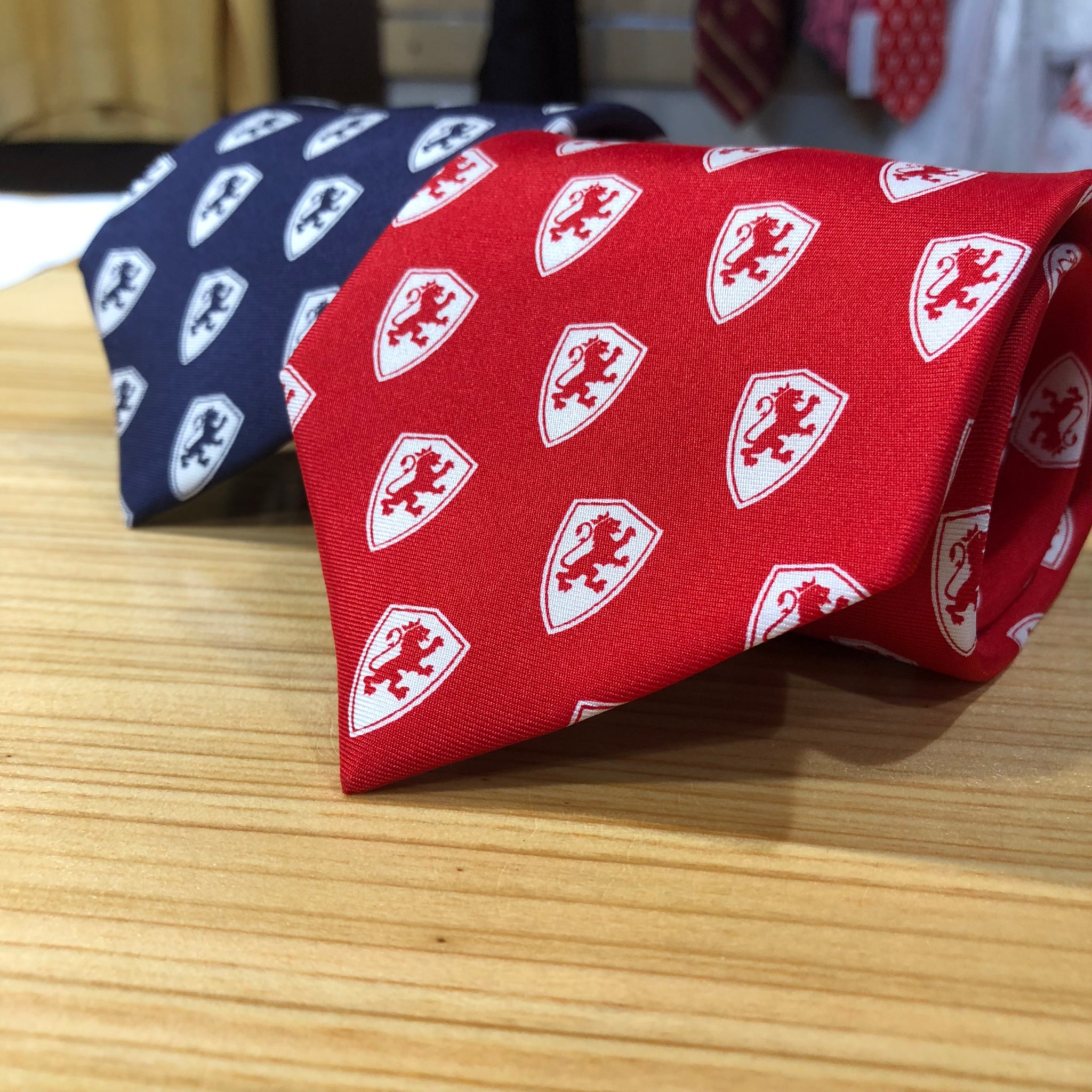 2 silk ties rolled up. dark blue with white Flagler college shield logos and crimson red with white Flagler college shield logos
