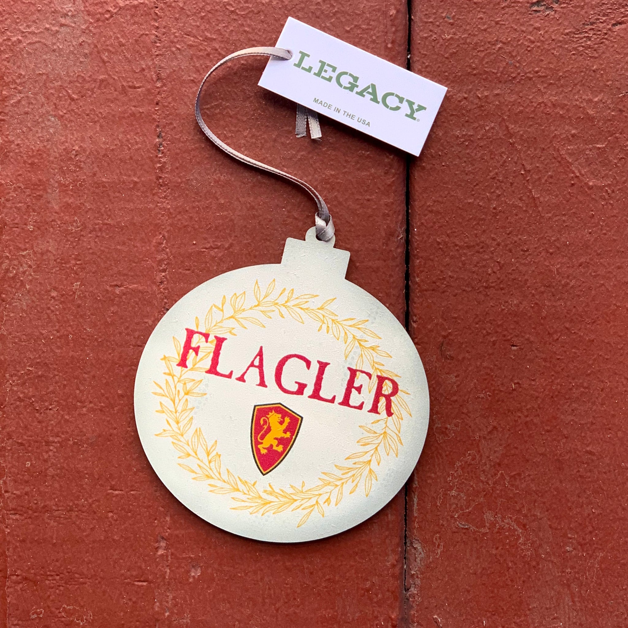 Round ornament that is a cream color with a gold wreath outlining ornament and it has flagler printed in red with red and gold lion shield