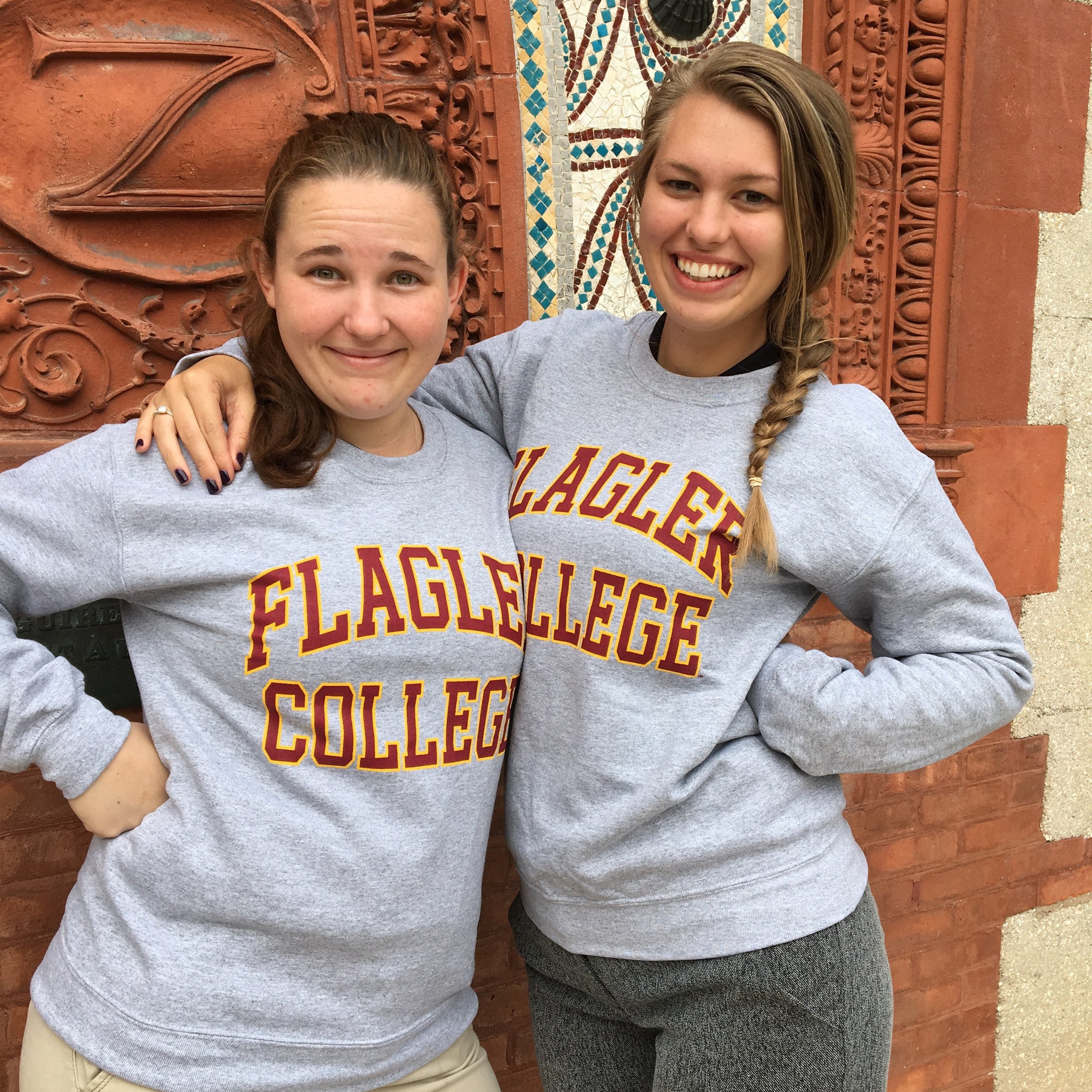 two individuals wearing grey crewnecks with crimson imprint saying Flagler over College
