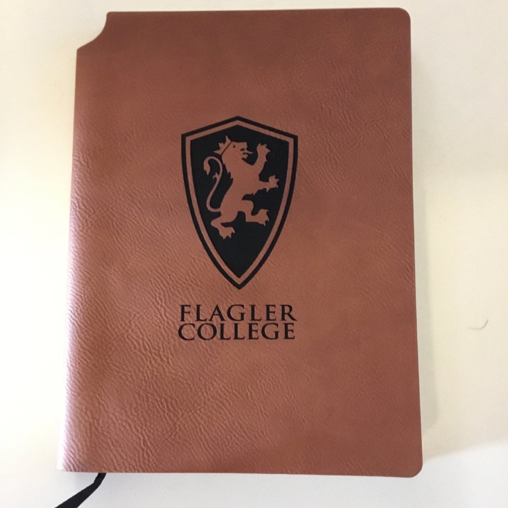 Brown velour journal with a large lion shield and "Flagler College" printed in black 